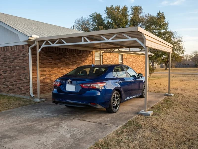Attached steel carport on the side of a single-story brick house sheltering a 2023 Toyota Camry