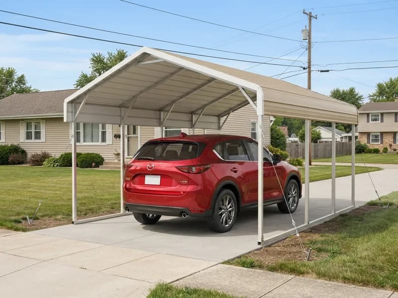 Portable steel carport with a gable roof anchored to the ground by cable stakes, sedan parked underneath