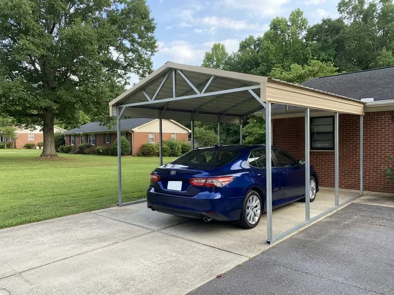 Attached steel carport on the side of a single-story house sheltering a 2023 Toyota Camry beside a lawn