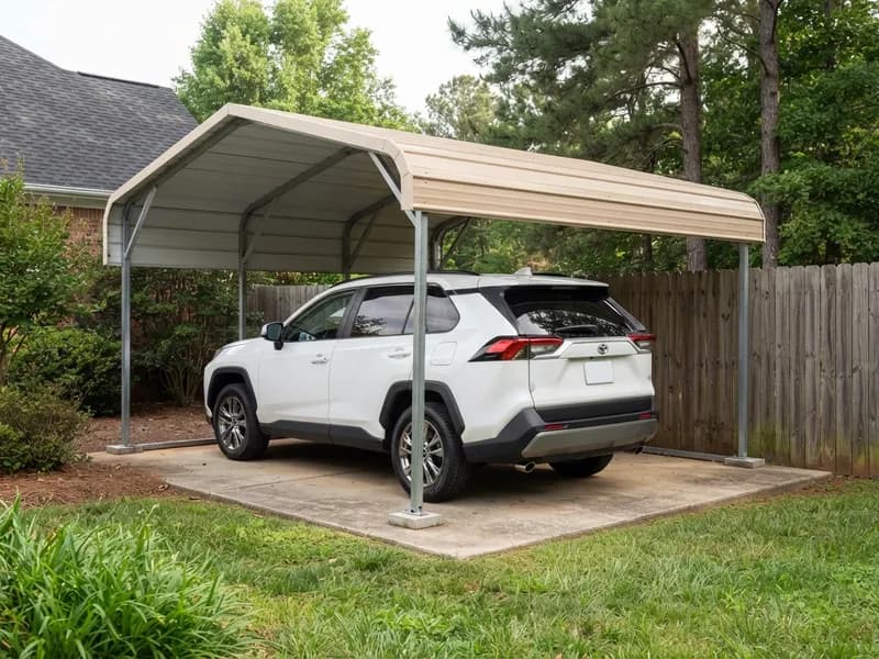 Detached steel carport beside a wood fence on a residential lot sheltering a 2022 Toyota RAV4