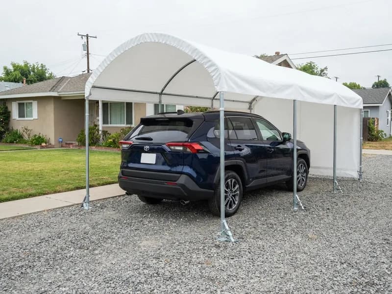Portable carport with white cover and steel frame over a 2022 Toyota RAV4 on a gravel driveway with ground anchors